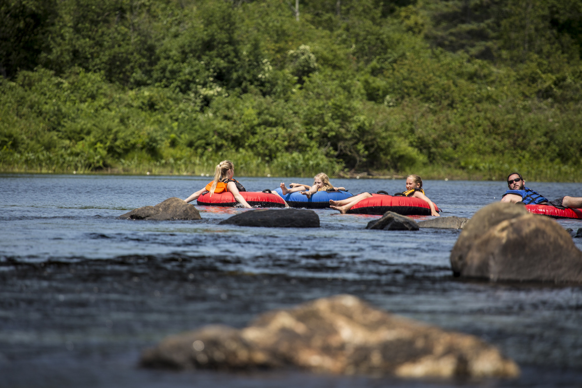 A group of people in lifejackets float down river on rafts on the Hudson.