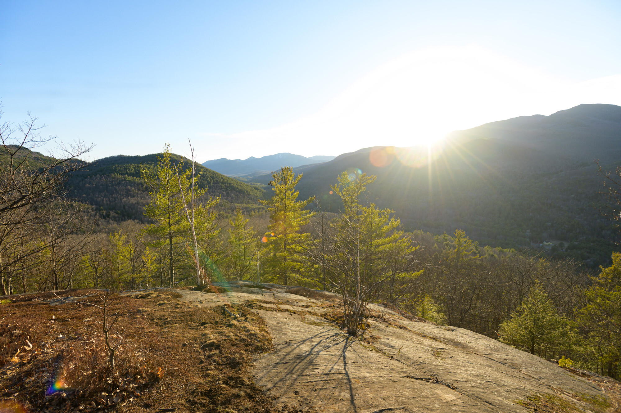 Sunlight shines over the ridge line of the mountains in the background and lights the summit in the foreground