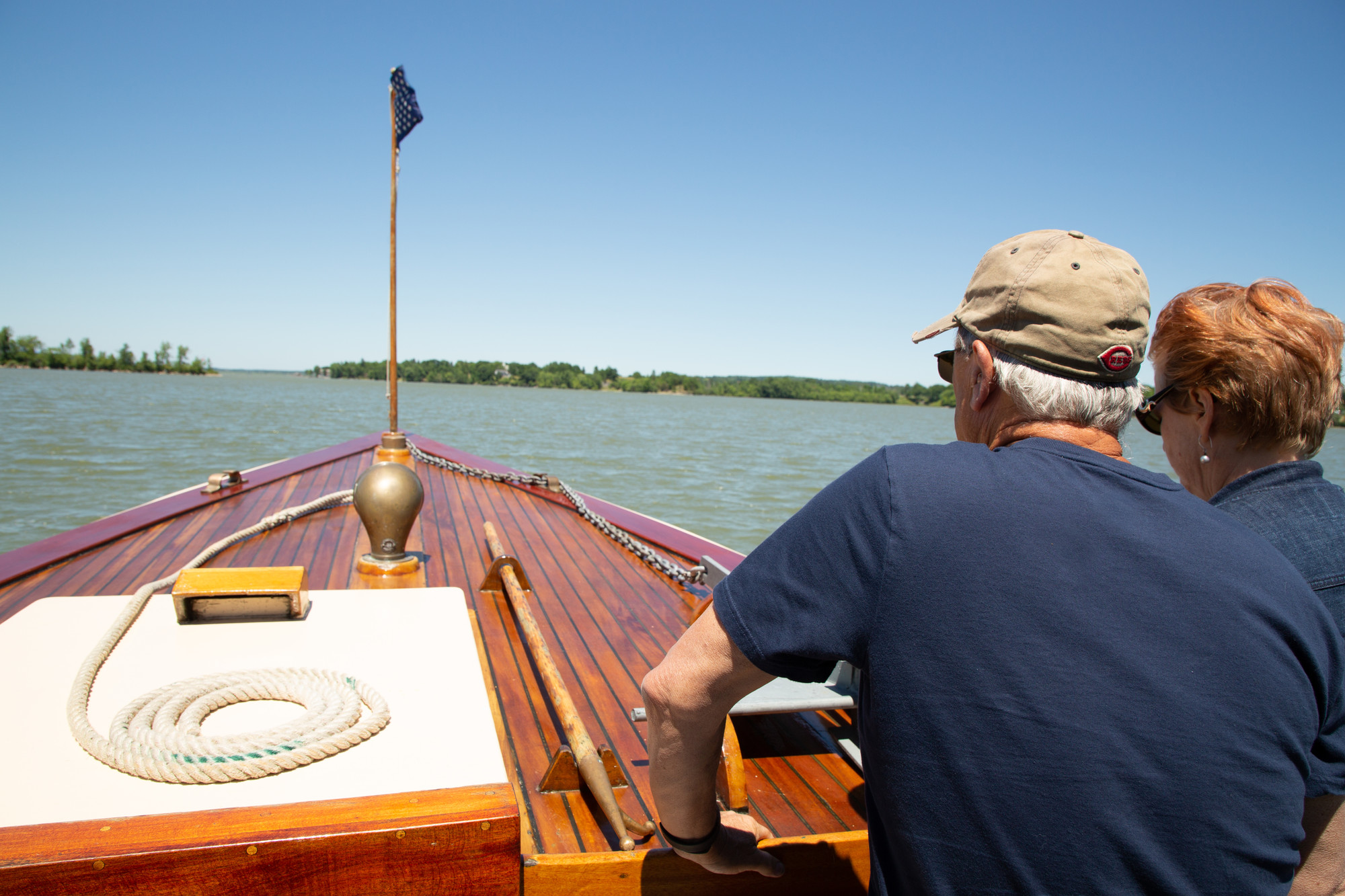 Two people stand on a guided boat overlooking the waters of Lake Champlain
