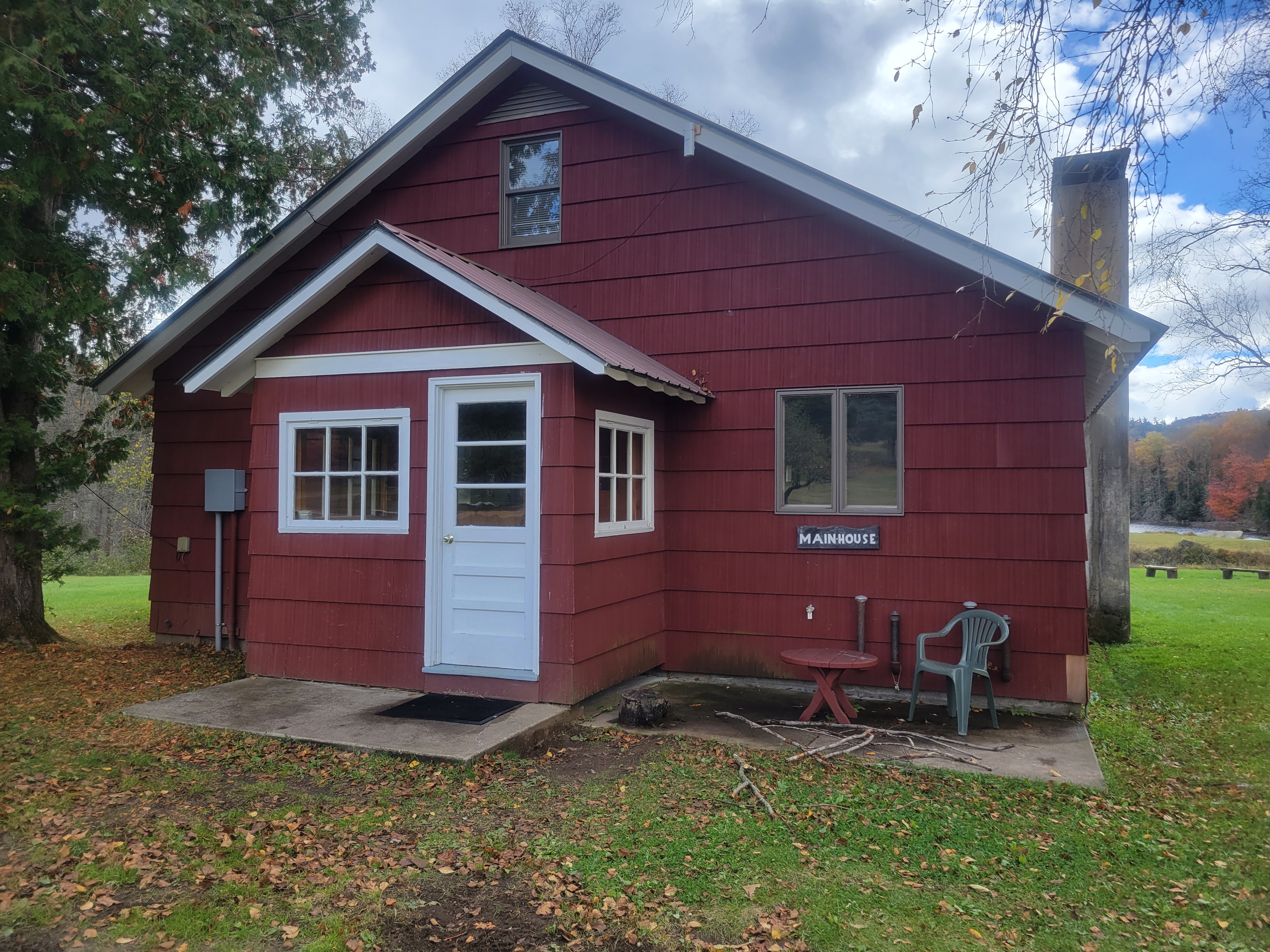 The front of a small, quaint red house with a chimney, known as the Main House at The Cabins at Chimney Mountain