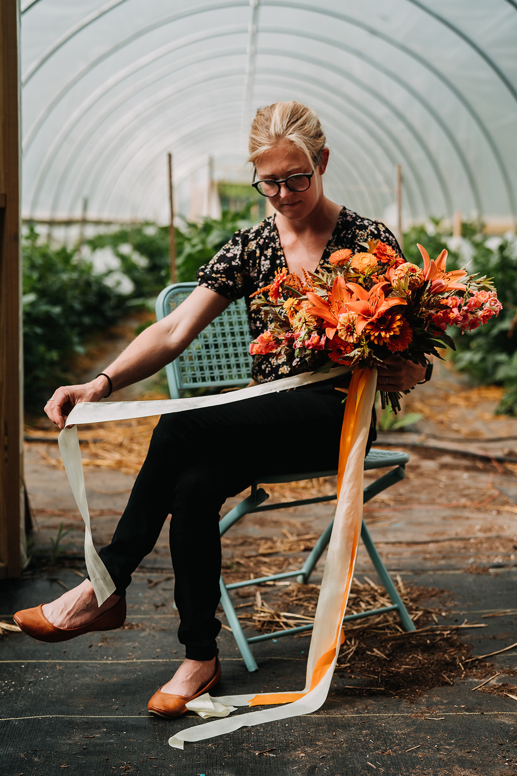 Linda creating a bouquet in front of one of the greenhouses. Image courtesy Due West Photography.