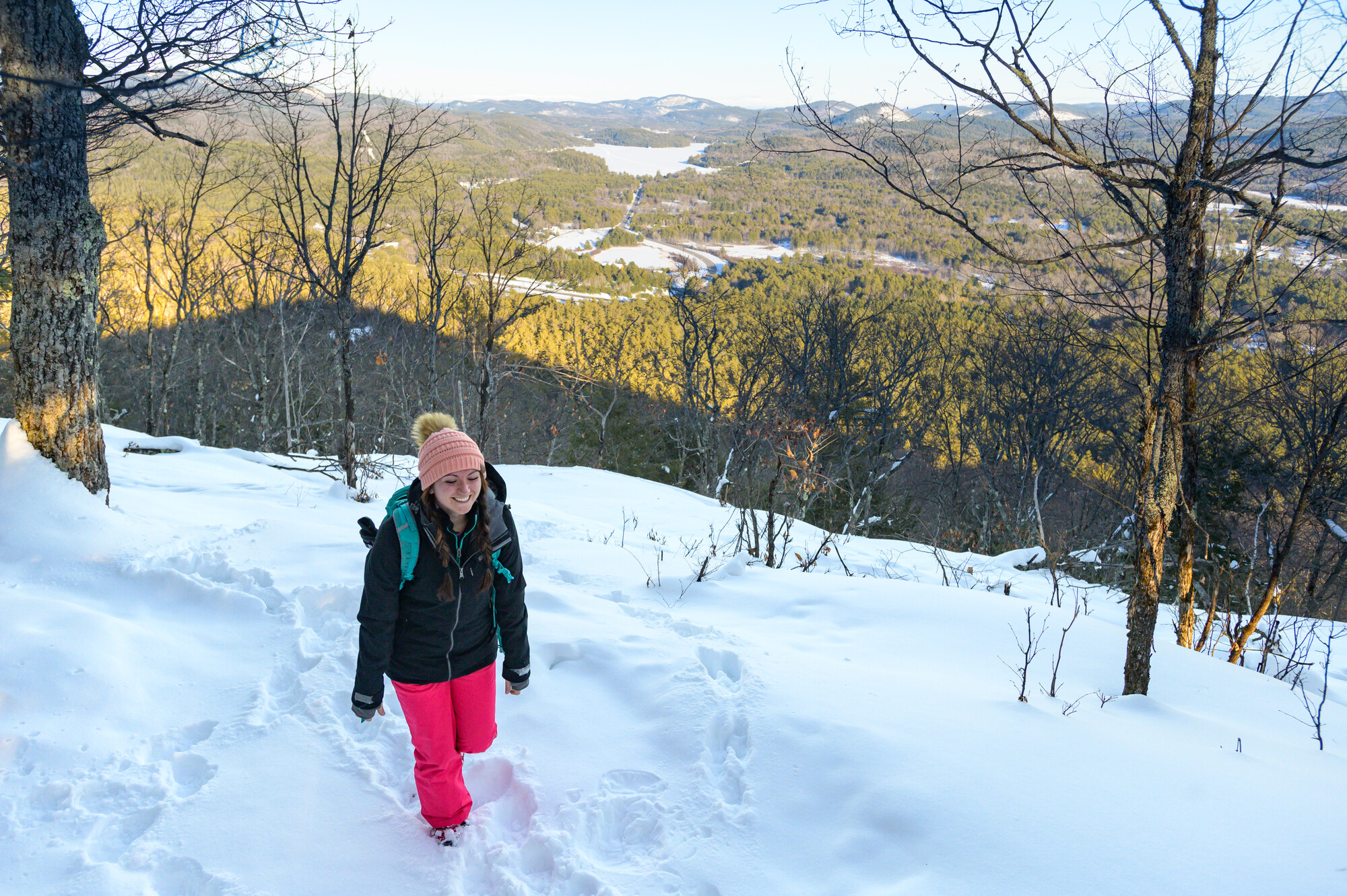 A woman snowshoes a trail on Mt Severance, with a sea of snow covered mountains in the background