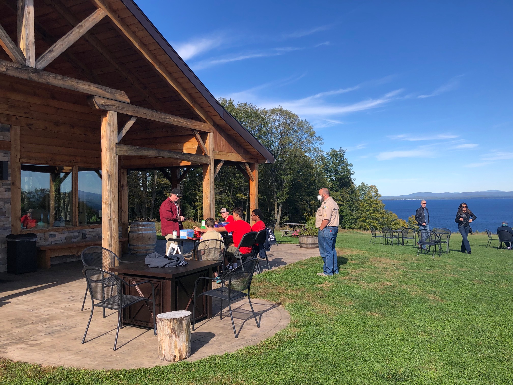 People stand outside a log building where wine tastings are offered.