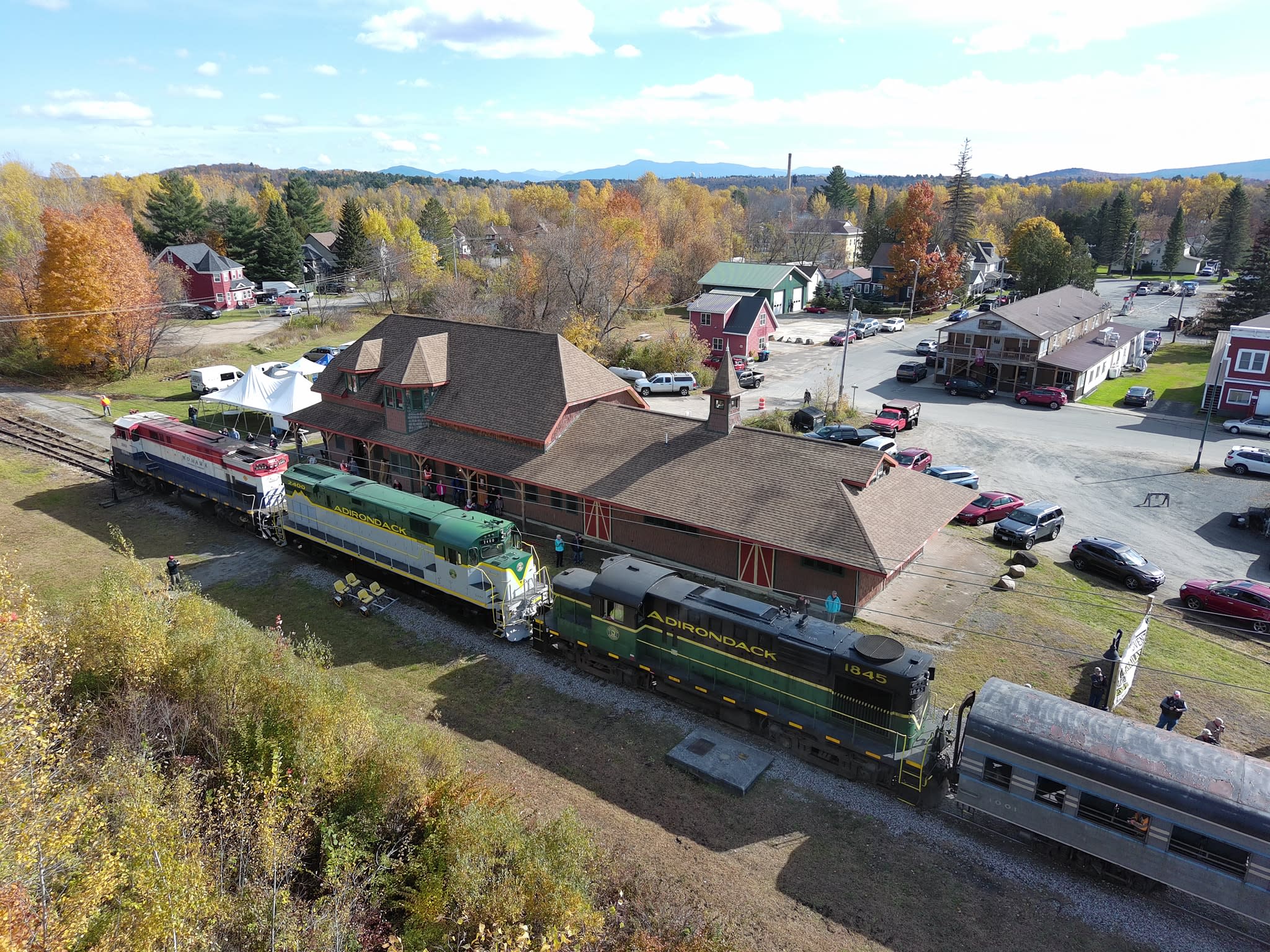 An aerial view of the restored Tupper Lake, NY train station, with a train standing on the tracks.