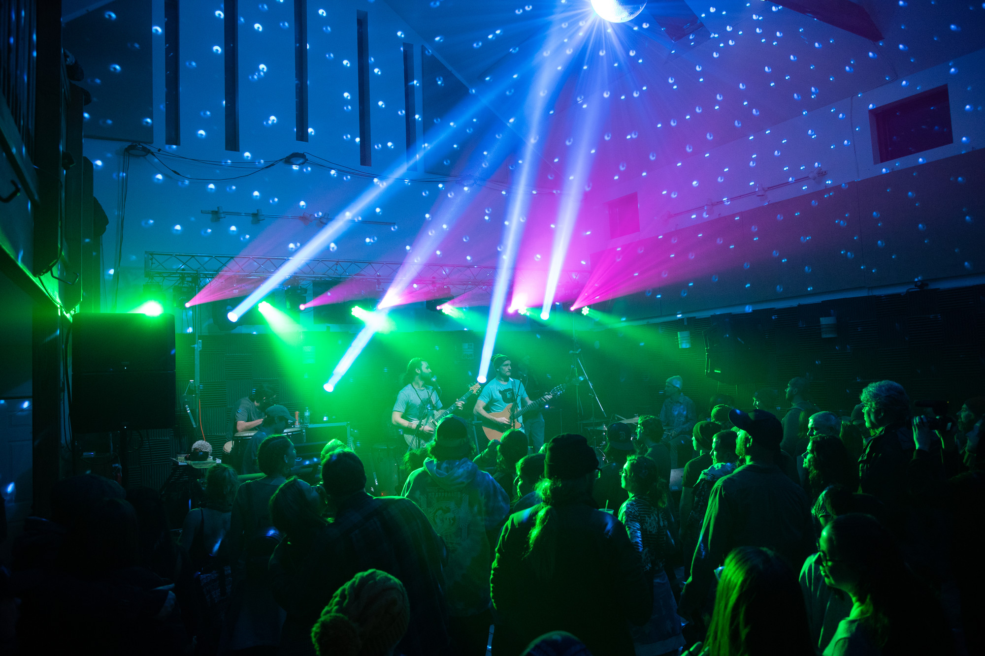 A band plays on stage complete with neon lights in front of a packed crowd 